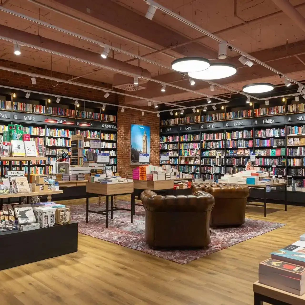 Innenraum einer Buchhandlung mit B&uuml;cherregalen voller unterschiedlicher Titel und gem&uuml;tlichen Sesseln zum Lesen